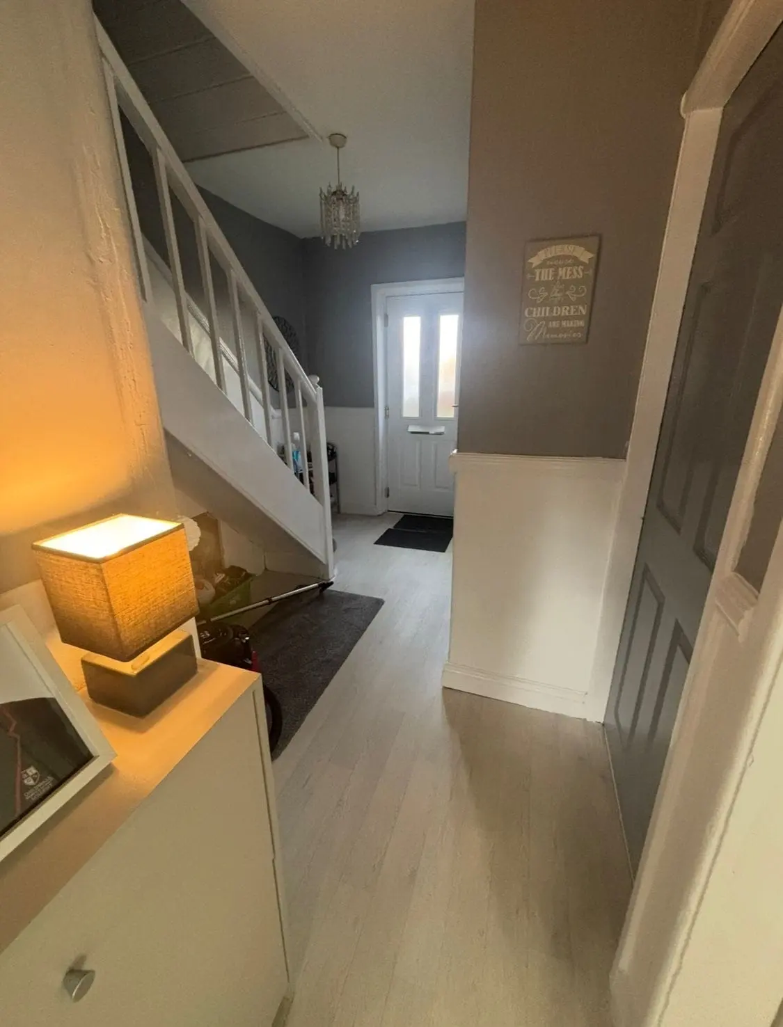 Hallway and staircase with grey upper walls, white lower panelling and a white front door